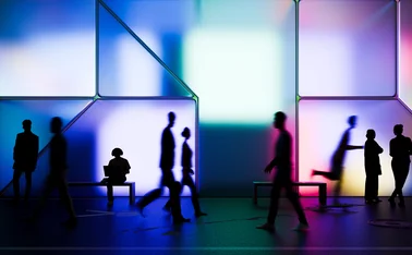 Night render of people walking in front of a building made of glowing cubes. All objects in the scene are 3D